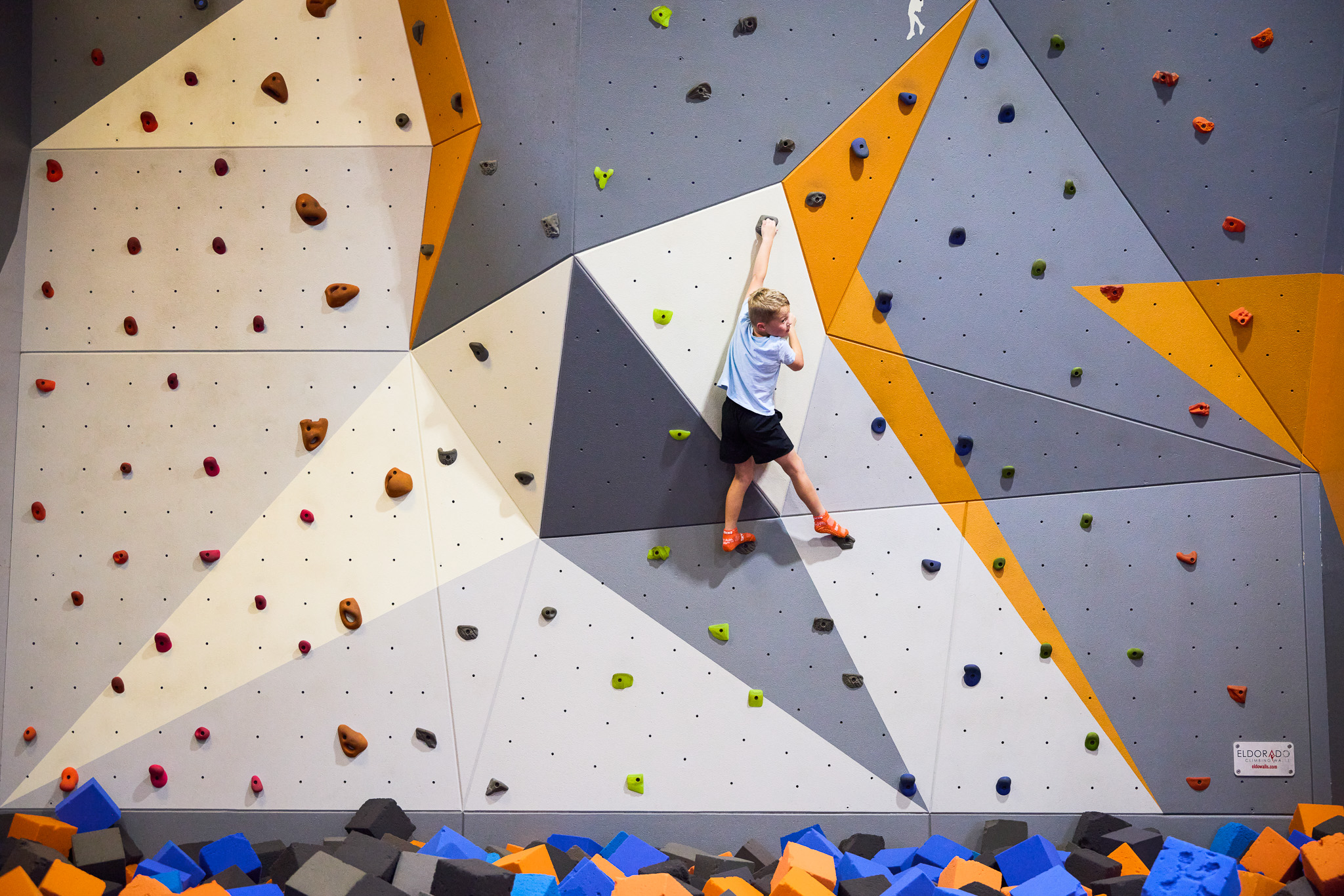 male child climbing a rock wall
