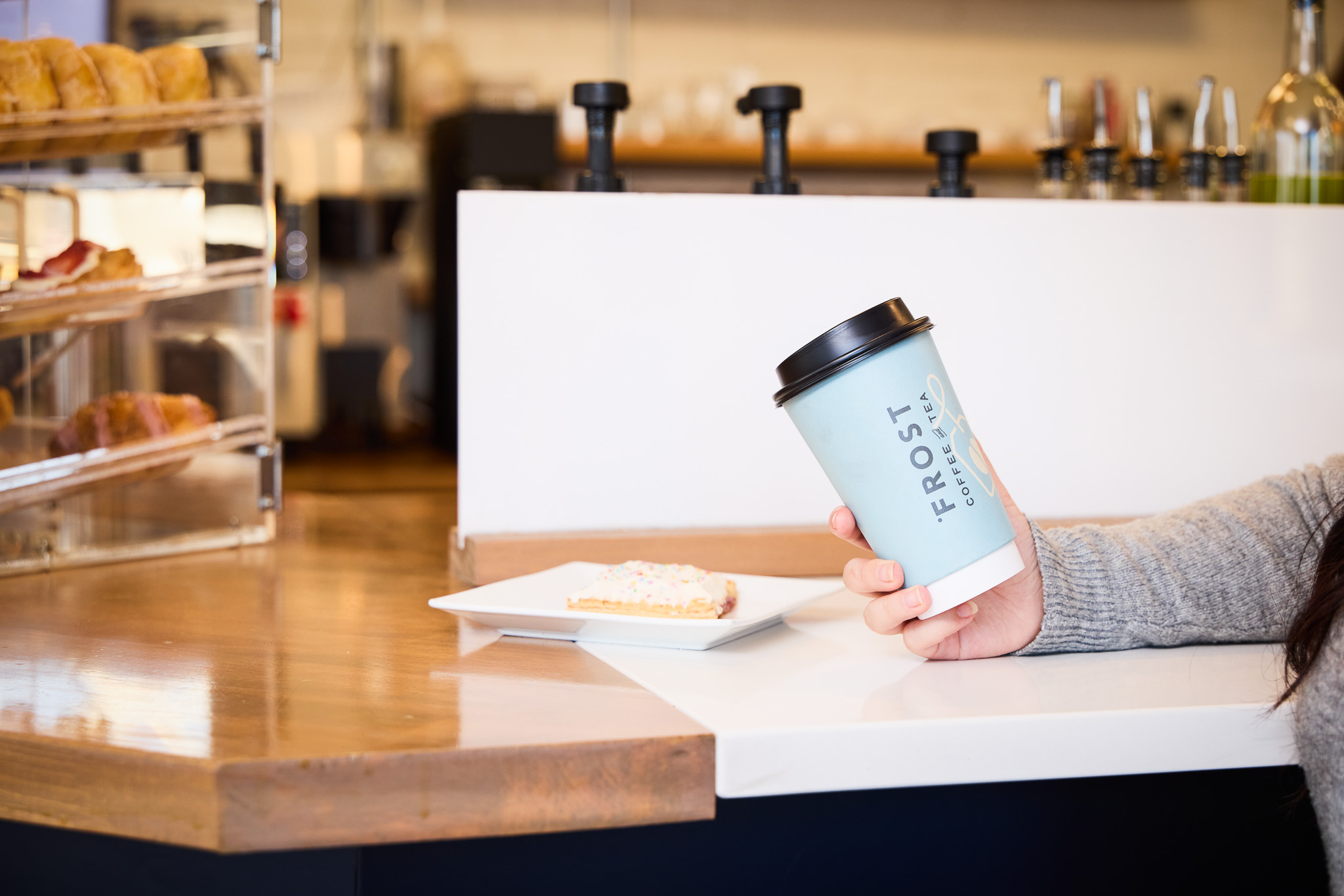image of a blue to-go coffee cup with the frost coffee and tea logo and a homemade poptart on a plate
