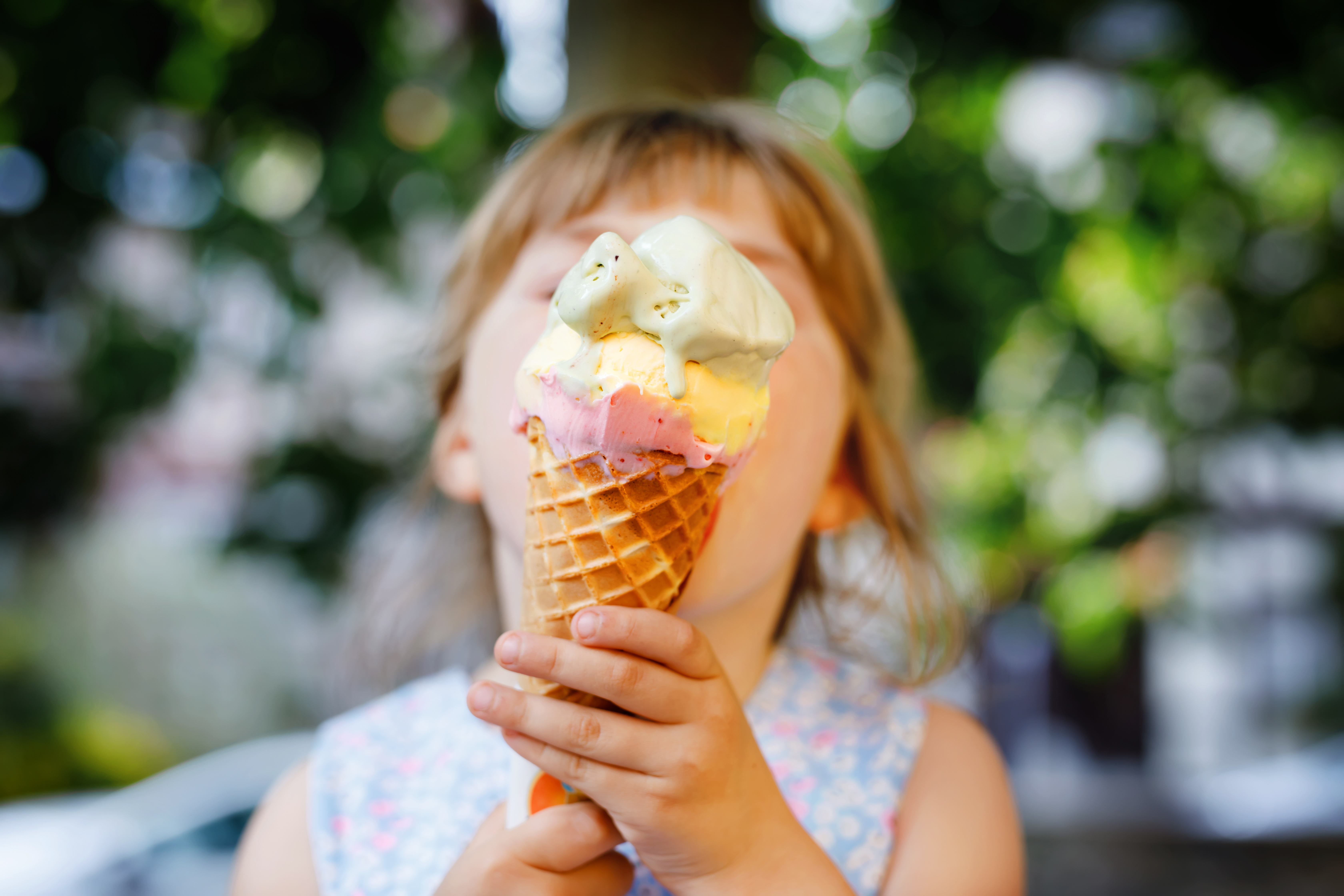 small child holding an ice cream cone in front of their face