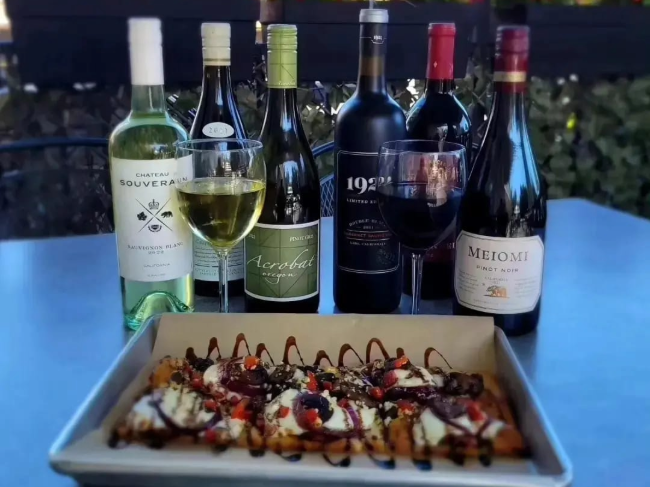 Variety of wine bottles and glasses of wine with a flatbread