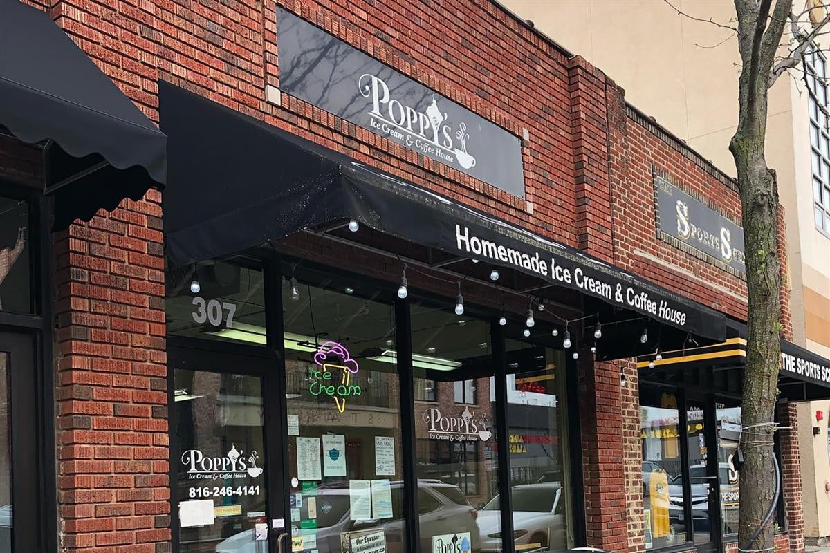 exterior of a brick building with a black rectangle sign saying Poppy's Ice Cream & Coffee House